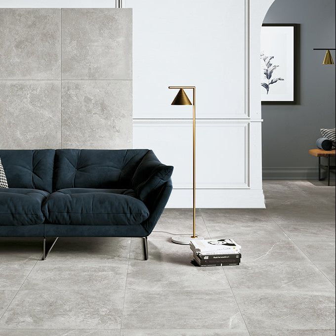 Modern living room with a dark blue sofa and gray tiled walls.