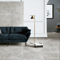 Modern living room with a dark blue sofa and gray tiled walls.