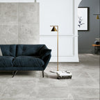 Modern living room with a dark blue sofa and gray tiled walls.